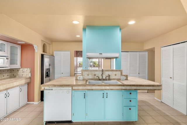 kitchen featuring blue cabinetry, white appliances, light countertops, and a sink