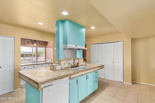 kitchen with blue cabinetry, a sink, recessed lighting, light tile patterned floors, and dishwasher