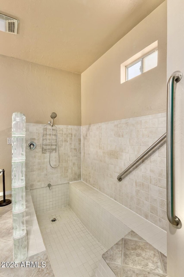 full bath with tile patterned flooring, visible vents, and a tile shower