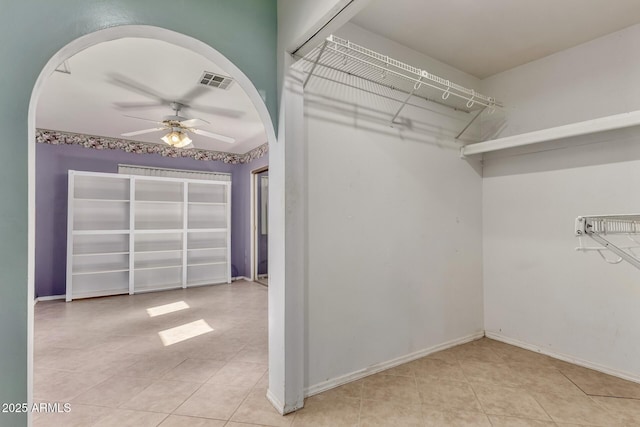 walk in closet featuring a ceiling fan, tile patterned floors, visible vents, and arched walkways