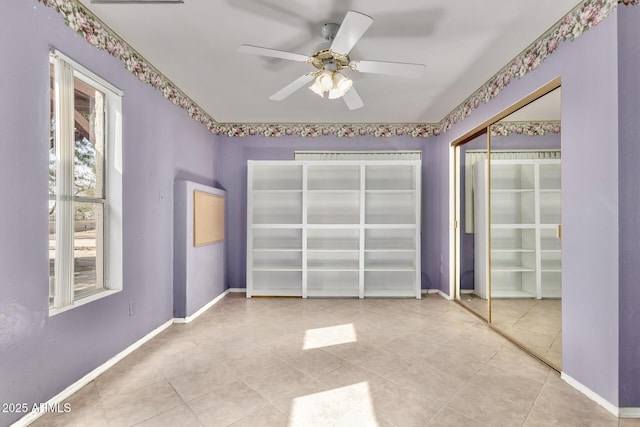 unfurnished bedroom featuring multiple windows, a ceiling fan, baseboards, and a closet