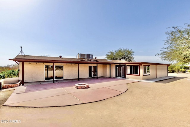 back of house with stucco siding, a patio, a fire pit, and central AC unit