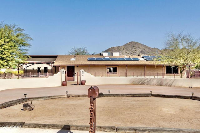 ranch-style home featuring a fenced front yard, roof mounted solar panels, and a mountain view