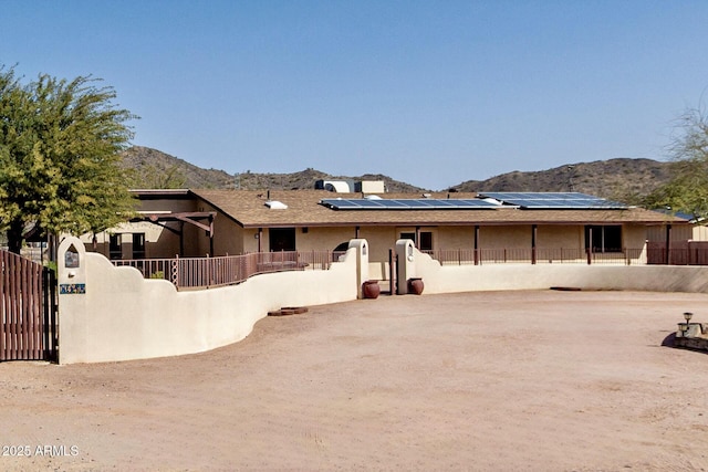 view of front of property featuring a mountain view, solar panels, fence private yard, and a gate