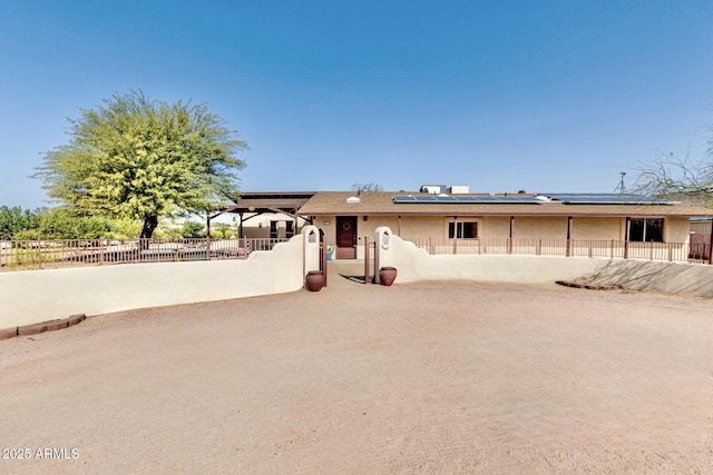 single story home with stucco siding, solar panels, and a fenced backyard