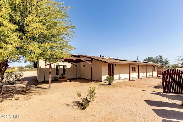 back of property with stucco siding, solar panels, and a gate