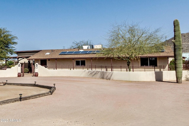 single story home with a fenced front yard, stucco siding, and solar panels