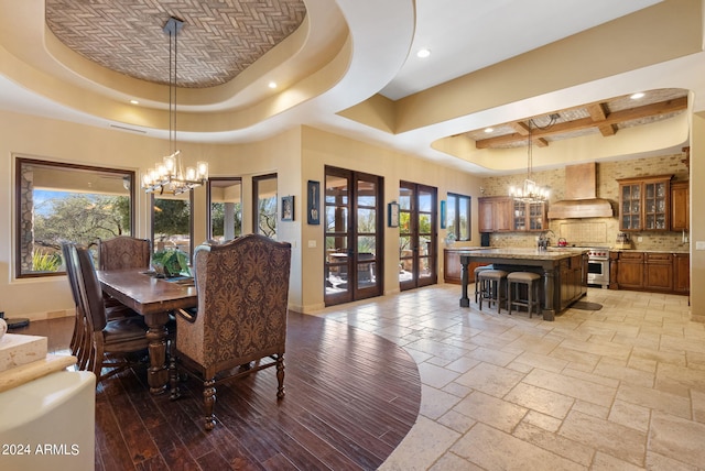 dining room featuring sink, an inviting chandelier, a towering ceiling, and a tray ceiling