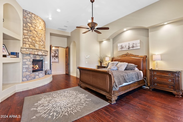 bedroom with ceiling fan, hardwood / wood-style flooring, and a stone fireplace