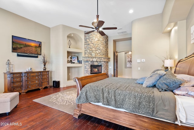 bedroom with ceiling fan, dark hardwood / wood-style flooring, and a stone fireplace