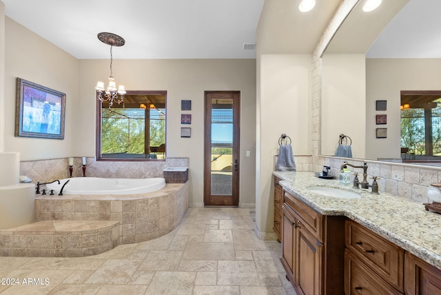 bathroom with tiled bath, a chandelier, and vanity