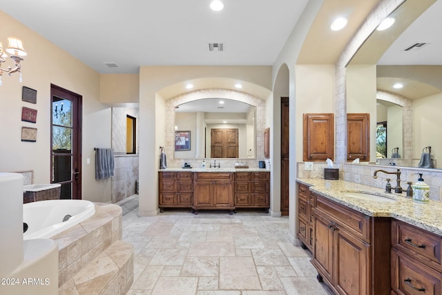 bathroom featuring tiled bath, decorative backsplash, and vanity