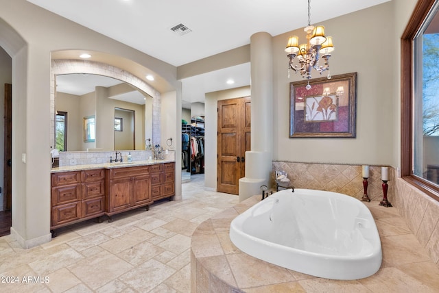 bathroom with vanity, tiled bath, and a notable chandelier