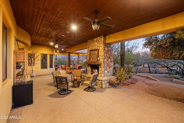 patio terrace at dusk featuring ceiling fan and an outdoor living space with a fireplace