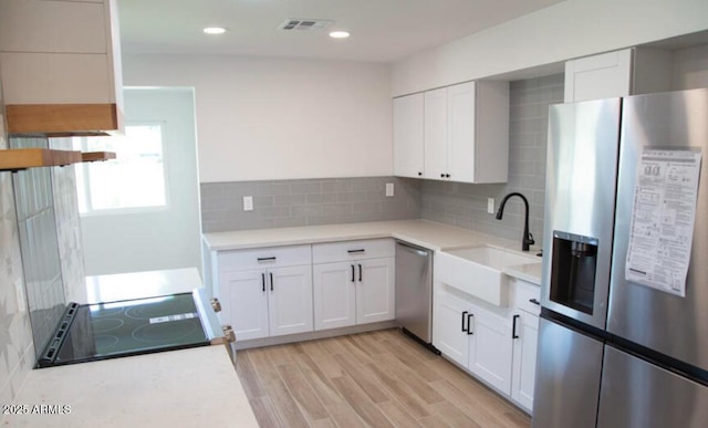 kitchen featuring light wood finished floors, visible vents, white cabinets, stainless steel appliances, and a sink