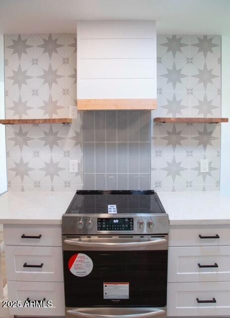 kitchen featuring tasteful backsplash, white cabinets, light countertops, and electric stove