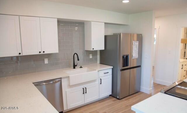 kitchen featuring a sink, decorative backsplash, appliances with stainless steel finishes, and white cabinetry