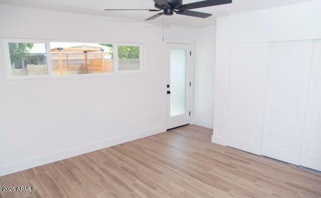 empty room featuring a ceiling fan, light wood-style floors, and baseboards