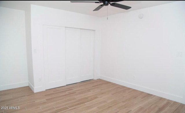 unfurnished bedroom featuring a closet, baseboards, light wood-style floors, and a ceiling fan