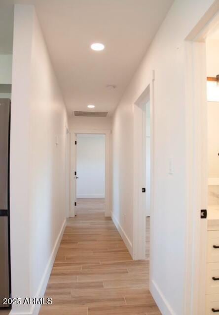 hall featuring recessed lighting, visible vents, baseboards, and light wood finished floors