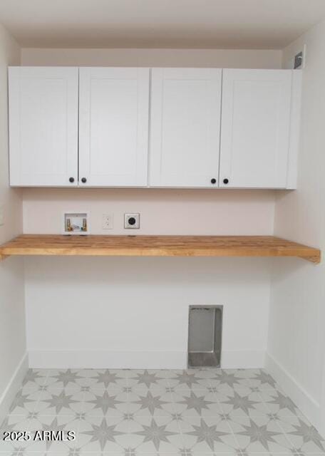 laundry area featuring cabinet space, baseboards, light floors, and electric dryer hookup