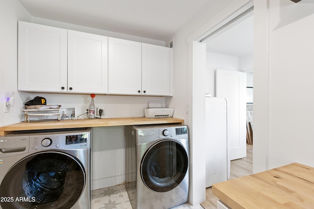 laundry area featuring washer and dryer, cabinet space, and light floors