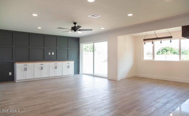 unfurnished living room with light wood finished floors, visible vents, recessed lighting, and baseboards