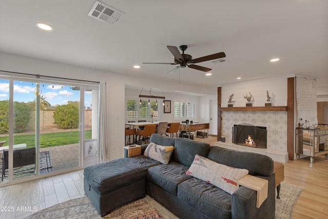 living area featuring a fireplace, recessed lighting, light wood-style floors, and visible vents