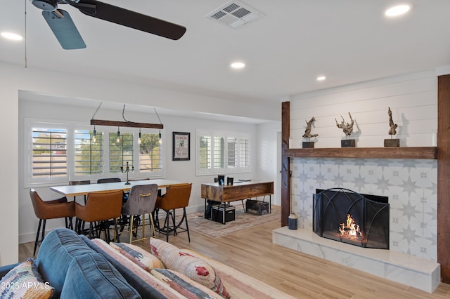 living area with visible vents, a ceiling fan, wood finished floors, recessed lighting, and a tile fireplace