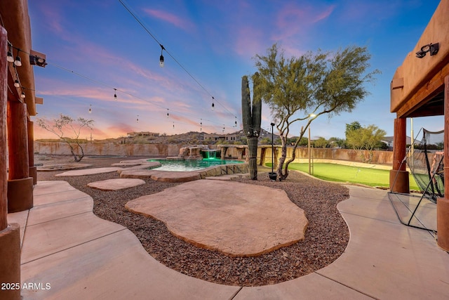 28758 N Ashbrook Ln, San Tan Valley, AZ 85144 - patio terrace at dusk with an area to practice putting, a patio area, and a fenced backyard