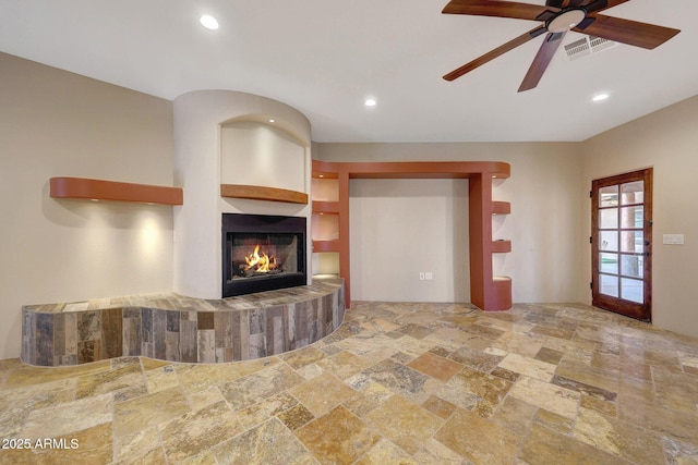 28758 N Ashbrook Ln, San Tan Valley, AZ 85144 - unfurnished living room with stone tile floors, a lit fireplace, a ceiling fan, and recessed lighting
