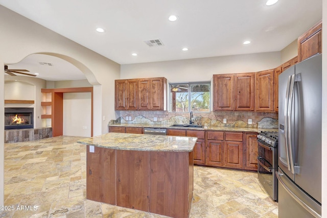 28758 N Ashbrook Ln, San Tan Valley, AZ 85144 - kitchen featuring stainless steel appliances, a sink, recessed lighting, light stone counters, and arched walkways
