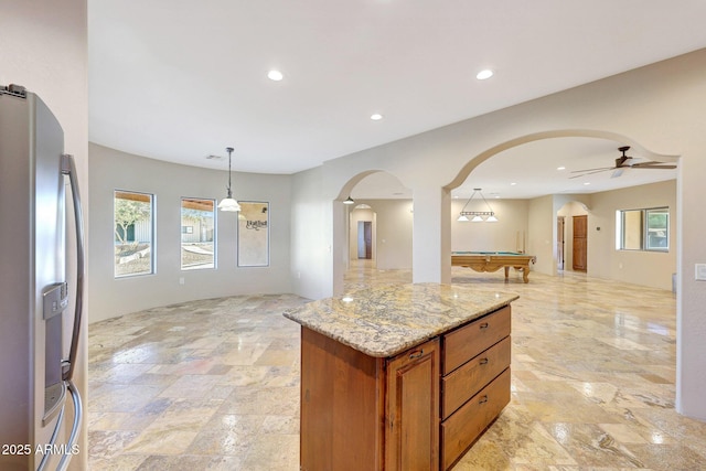 28758 N Ashbrook Ln, San Tan Valley, AZ 85144 - kitchen with stainless steel fridge with ice dispenser, arched walkways, open floor plan, brown cabinetry, and billiards table
