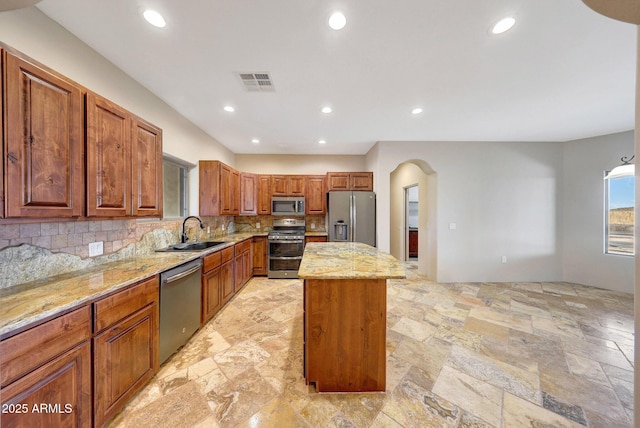 28758 N Ashbrook Ln, San Tan Valley, AZ 85144 - kitchen with stainless steel appliances, a sink, a center island, light stone counters, and backsplash