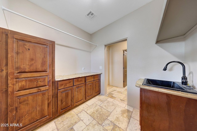 28758 N Ashbrook Ln, San Tan Valley, AZ 85144 - kitchen with stone tile floors, a sink, and brown cabinets