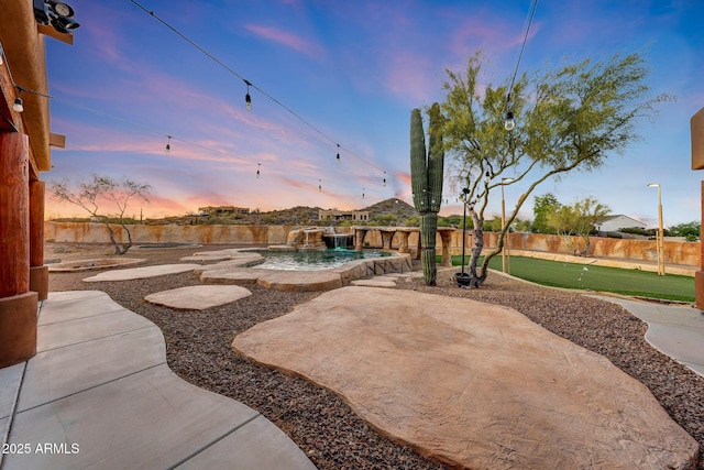 28758 N Ashbrook Ln, San Tan Valley, AZ 85144 - patio terrace at dusk featuring a putting area, a patio area, a pool, and a fenced backyard