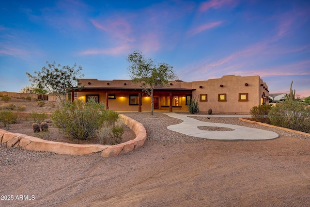 28758 N Ashbrook Ln, San Tan Valley, AZ 85144 - back of property at dusk with a porch and stucco siding