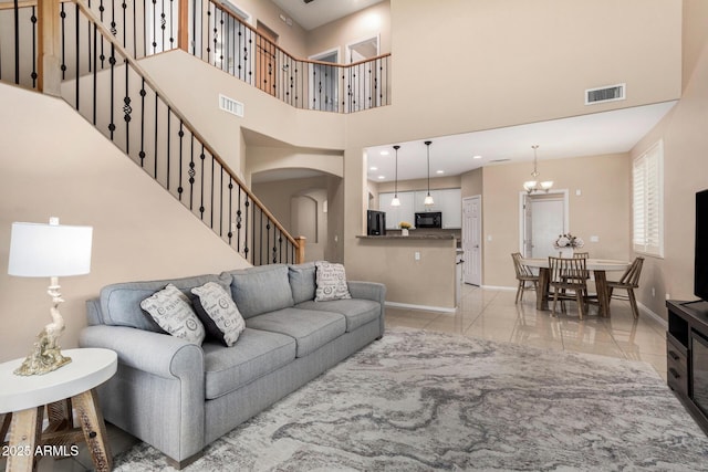 12023 W Duane Ln, Peoria, AZ 85383 - living area with baseboards, a towering ceiling, arched walkways, a chandelier, and stairway