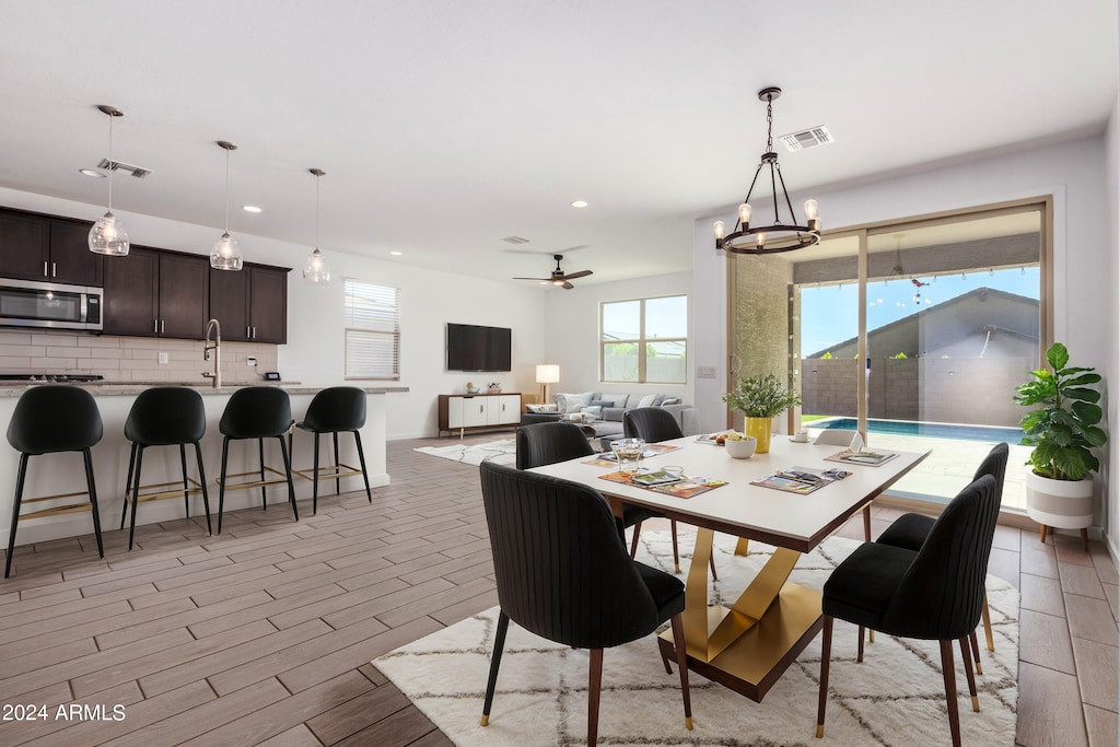 dining space featuring ceiling fan with notable chandelier and light wood-type flooring