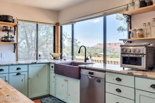 kitchen featuring a sink, light stone counters, open shelves, and stainless steel dishwasher