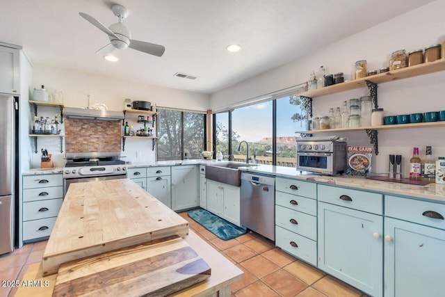 kitchen with light tile patterned floors, open shelves, visible vents, appliances with stainless steel finishes, and a sink