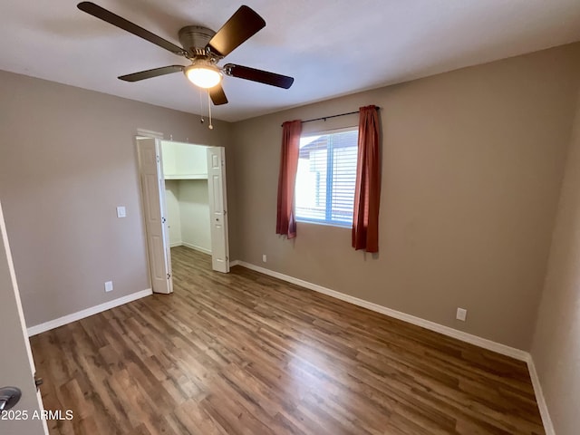 unfurnished bedroom with a walk in closet, dark hardwood / wood-style floors, ceiling fan, and a closet