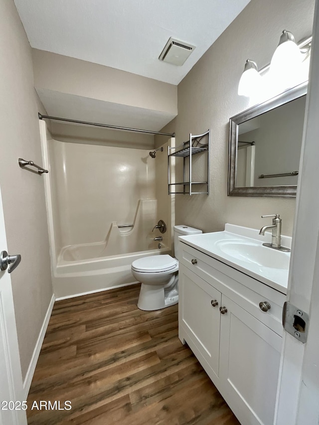 full bathroom with hardwood / wood-style flooring, vanity, washtub / shower combination, and toilet