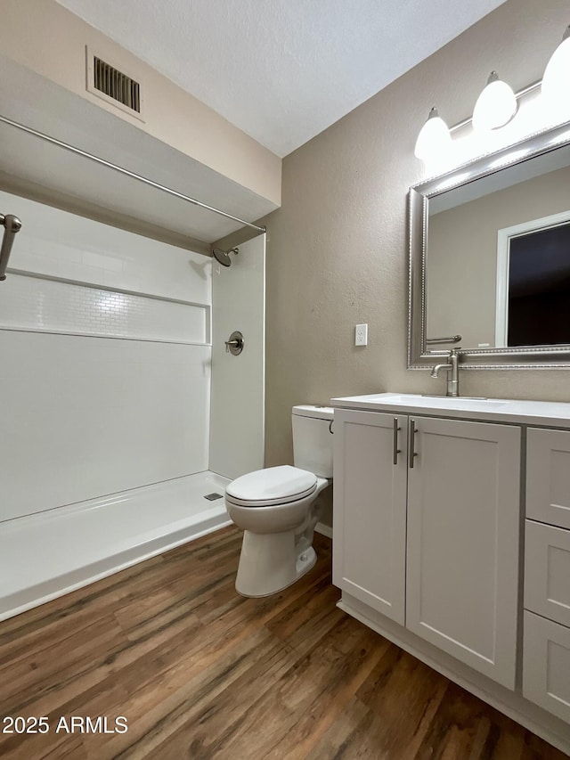 bathroom with hardwood / wood-style floors, a shower, vanity, toilet, and a textured ceiling