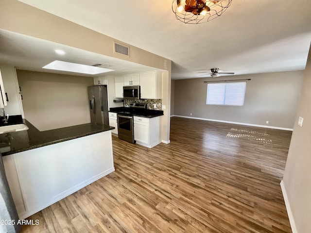 kitchen featuring hardwood / wood-style floors, decorative backsplash, white cabinets, and appliances with stainless steel finishes