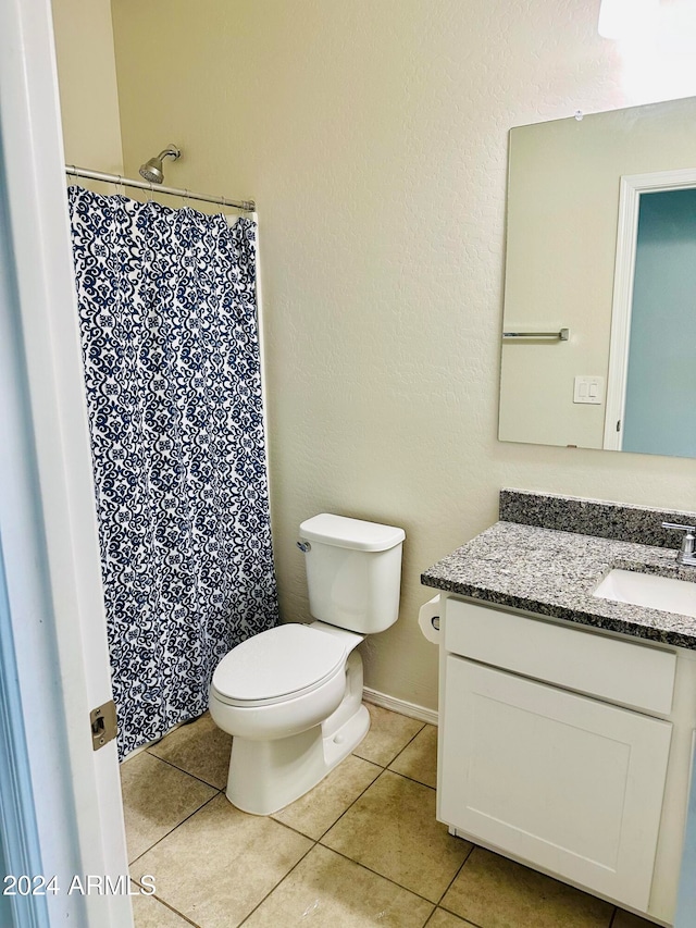 bathroom with tile patterned flooring, vanity, toilet, and walk in shower