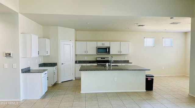 kitchen with sink, dark stone countertops, an island with sink, appliances with stainless steel finishes, and white cabinetry