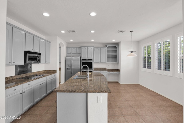 kitchen with a sink, visible vents, hanging light fixtures, appliances with stainless steel finishes, and a center island with sink