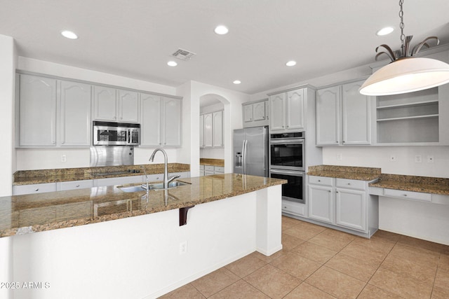 kitchen with visible vents, appliances with stainless steel finishes, dark stone countertops, open shelves, and a sink