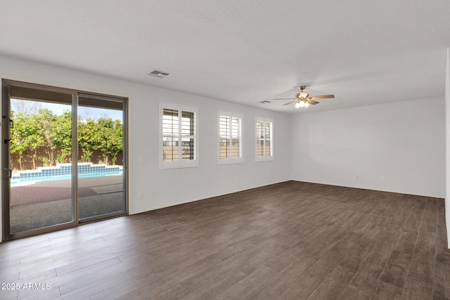 spare room with dark wood finished floors, visible vents, and a healthy amount of sunlight